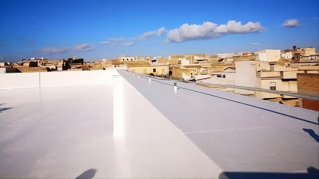 Copertura piana bianca impermeabilizzata, con il paese sullo sfondo